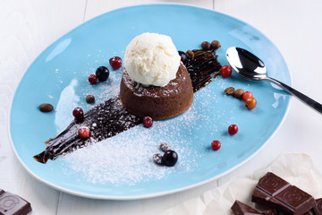 Chocolate fondant with ice cream, pieces of chocolate and coffee on a white table