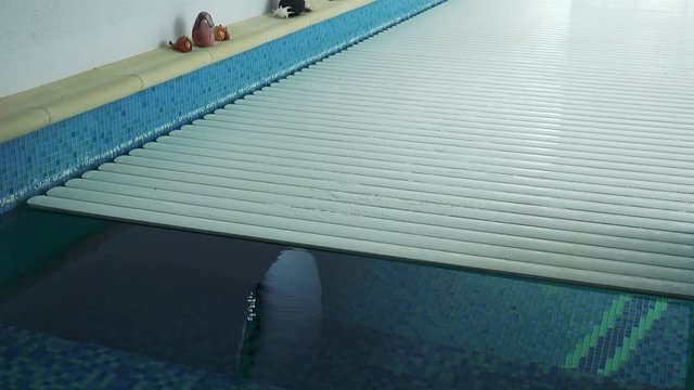 An automatic indoor swimming pool cover rolls away