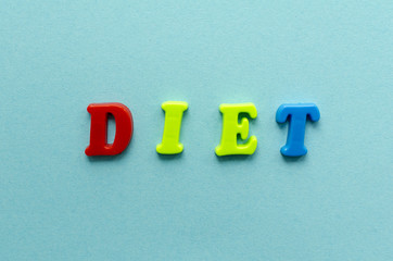 word 'diet' from plastic colored magnet letters on blue paper background
