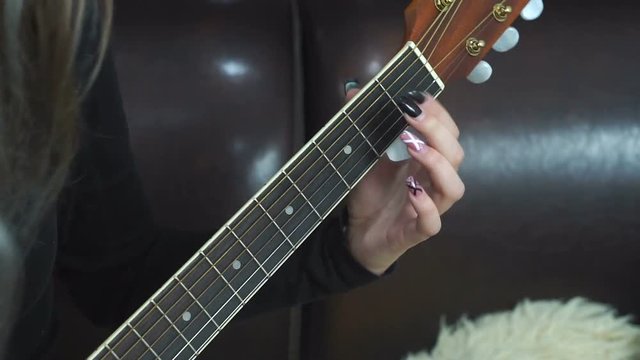 Closeup of young woman's hand, strumming the guitar