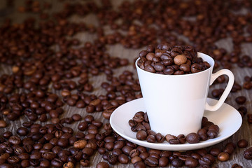 Coffee concept: fried coffee beans in porcelain white coffee cup
