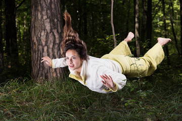 Flying in a dream. Young woman in pajamas in summer green forest in a state of weightlessness