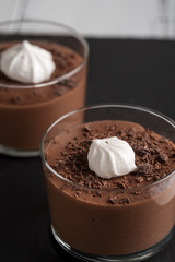 Chocolate mousse in a glasses on a black stone background.