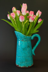 Pink tulips in a turquoise vase on a dark background