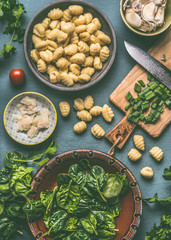 Potato gnocchi with spinach and vegetarian cooking ingredients on rustic table , top view