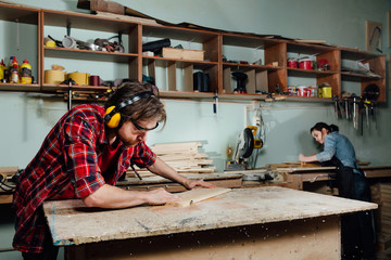 Two carpenters work hard in the workshop. A man and a woman.