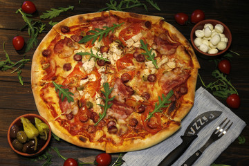 Pizza with bacon, sausages, ham, tomato and olives. Sprinkle with arugula and served with tomato and cheese. Pizza Restaurant. Snack, dinner