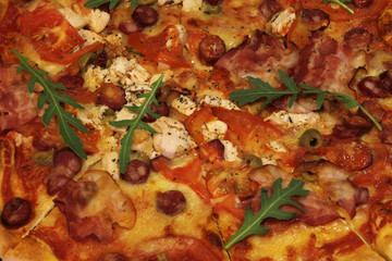 Pizza with bacon, sausages, ham, tomato and olives. Sprinkle with arugula and served with tomato and cheese. Pizza Restaurant. Snack, dinner