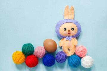 Easter rubbit toy with egg and multi-colored ball on the blue backgraund