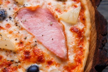 Food background, pizza texture. Close up of appetizing pizza with ham and black olives, macro