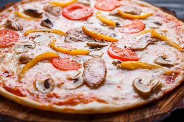 Appetizing yummy pizza with tomato, chicken, paprika and mushrooms, close up