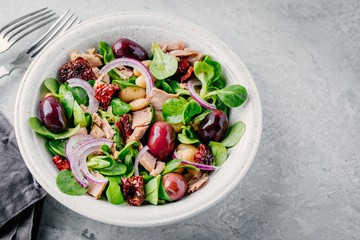 salad with white beans, tuna, olives, red onions and dried tomatoes with green lettuce leaves