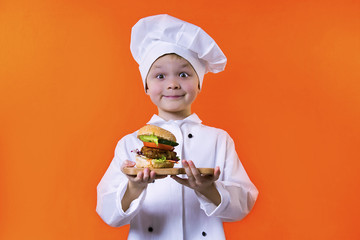 funny boy chef holding a sandwich on a board on a bright orange background