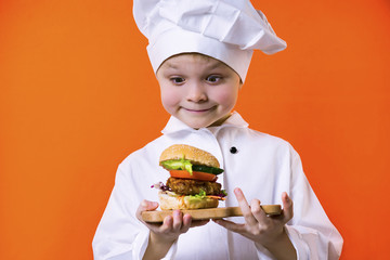 funny boy chef holding a sandwich on a board on a bright orange background