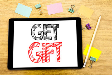 Writing text showing Get Gift. Business concept for Free Shoping Coupon Written on tablet laptop, wooden background with sticky note and pen