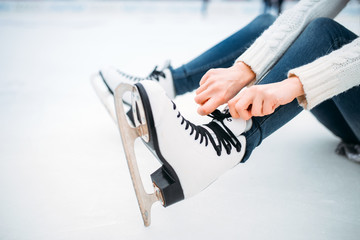 Fototapeta na wymiar Young woman ties the shoelaces on skates