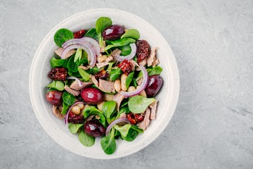 salad with white beans, tuna, olives, red onions and dried tomatoes with green lettuce leaves