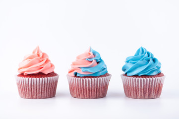 Cupcakes red velvet with blue and pink whipped cream on white background. Picture for a menu or a confectionery catalog.
