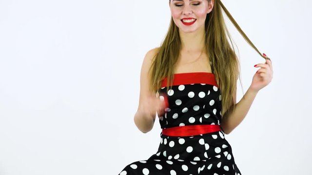 A beautiful 50s pin-up girl sits on a stool, moves in rhythm of music and smiles at the camera - white screen background