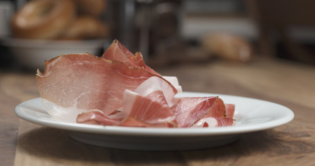 sliced prosciutto on white plate on wood table