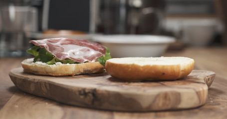 bagel sandwich with coppa and cream cheese on wood board