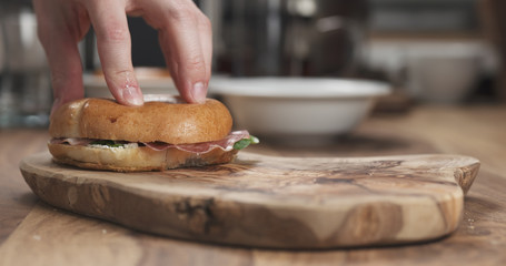 bagel sandwich with coppa and cream cheese on wood board