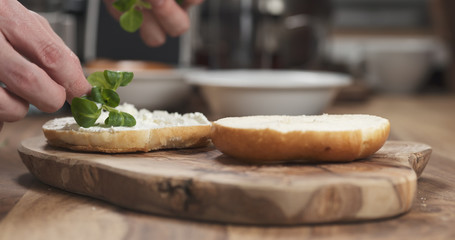 Man hands making bagel sandwich on wood board