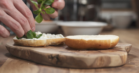 Man hands making bagel sandwich on wood board