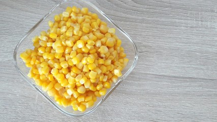 corn kernels in a glass cup on a wooden background