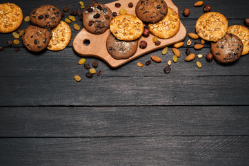 Freshly baked cookies on a wooden table. Lies on a wooden dostichke, around various nuts and raisins.