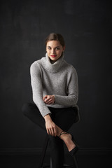 Portrait of beautiful young woman looking at camera and smiling while posing at dark background.