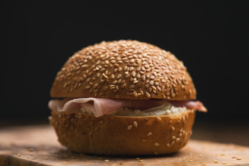 prosciutto and cream cheese in a sesame bun on wood board