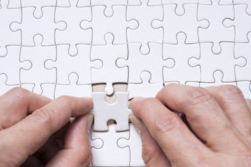 Hand business with white blank jigsaw puzzle piece. Business concept for complete and teamwork.