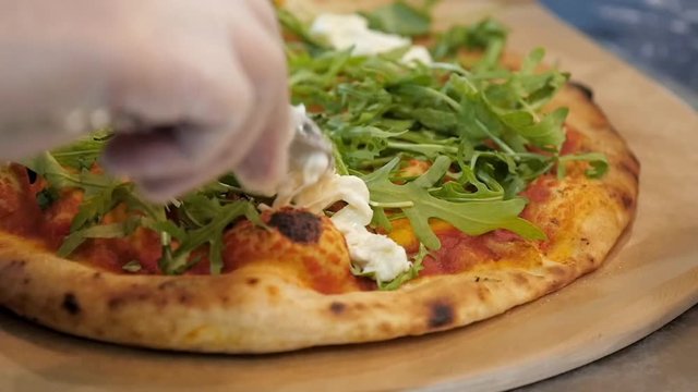 Chef puts stracciatella cheese on pizza