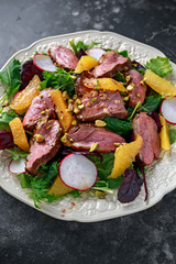 Duck breast fillets steak salad with orange halves, radishes and crushed pistachios