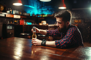 Man sitting at the bar counter and opens bottle