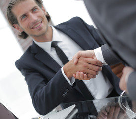 handshake business partners in front of the open laptop