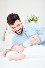 Obraz na płótnie Canvas Liebevoller Vater gibt Baby die Flasche