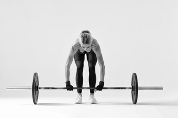 Fototapeta na wymiar Fitness attractive woman preparing to practice deadlift with heavy weights Female bodybuilder doing heavy weight lifting work out on white background Black and white horizontal picture