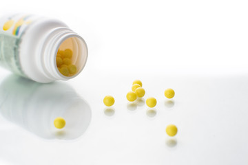 Scattered vitamins on a white background round and yellow, falling from a jar