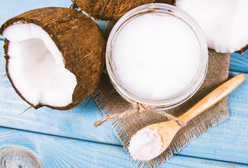 Coconut oil and fresh coconuts on a wooden table.