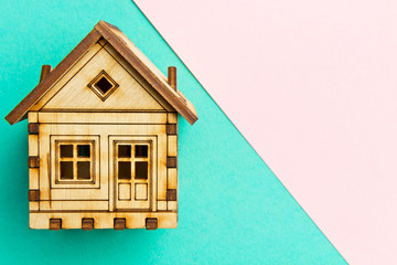 Fototapeta na wymiar Wooden model house on a Geometric pink and turquoise pastel background with copy space. Pattern, form. Wooden house handmade.