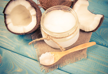 Coconut oil and fresh coconuts on a wooden table.