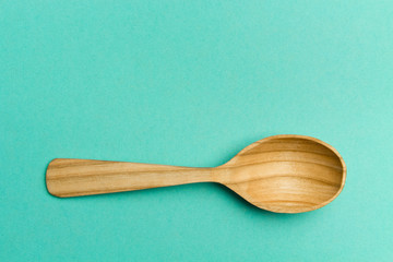 Wooden spoon on a turquoise background.Spoon with textured tree. Trend Colors . Copy space