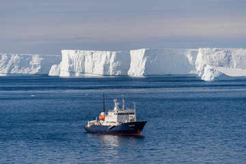 Expedition ship with iceberg aerial view