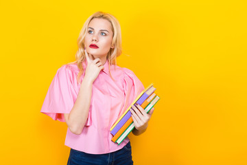 Blonde woman in pink blouse with pile of books