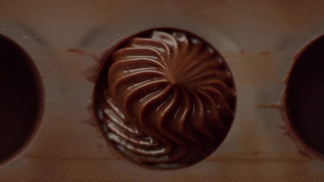 closeup of pastry bag filling candy mold form with chocolate cream Top view macro