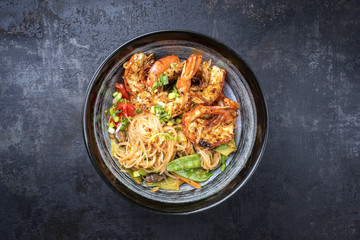 Traditional Thai Phak Kung curry with barbecue king prawns and noodles as top view in a bowl