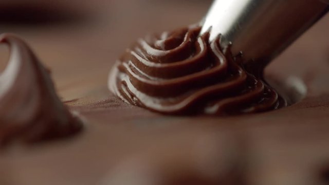 closeup of pastry bag filling candy mold form with chocolate cream. Macro cream texture