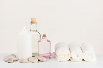 Fototapeta na wymiar Spa soft light composition with burning candle, terry towels, glass bottles and stones